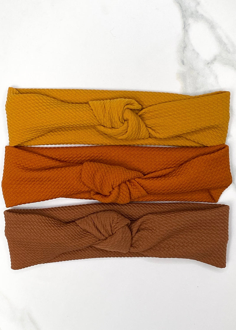 knotted baby headbands in burnt orange, mustard yellow, and brown. 